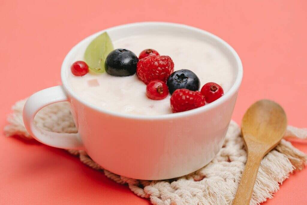 Xícara com iogurte e frutas vermelhas por cima
