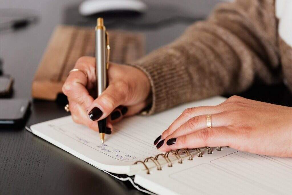 Pessoa escrevendo em sua agenda