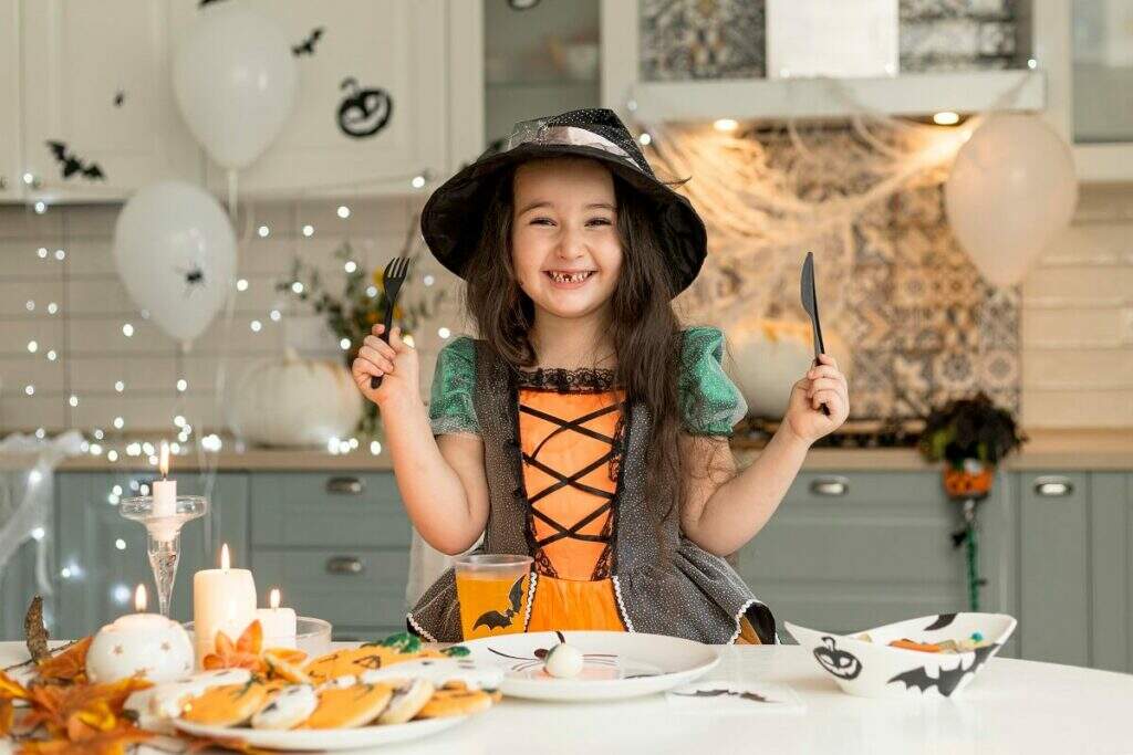 Menina criança com fantasia de bruxa fazendo receitas temáticas de halloween