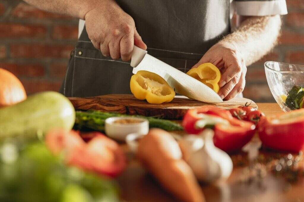 pessoa picando vegetais em uma bancada da cozinha